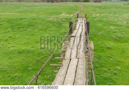 Eearly Spring Landscape With Ancient Wooden Foot-bridge Through Local Meadow Over  Small River Tomak
