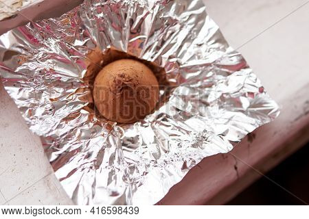 A Chocolate Truffle Candy Wrapped In A Foil Wrapper On An Old Wooden Windowsill