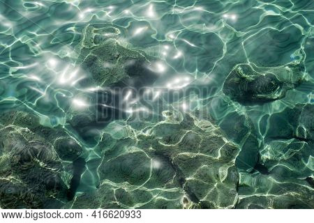 Transpatent Aquamarine Sea Water Gleaming In Sunlight And Rocks Underwater