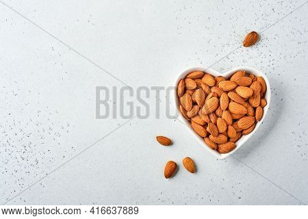 Almond Nut In A Heart-shaped Ceramic Plate On White Background With Copy Space. Snack Vegan Sugarfre