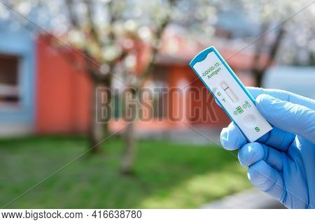 Hand Holds Quick Test Outdoors, With Office, School Or Kindergarden Building Out Of Focus. Express C