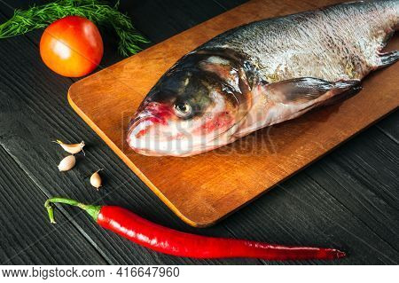 Hypophthalmichthys Or Bighead Carp On A Cutting Board With Vegetables Before Cooking. Raw Peeled Fis