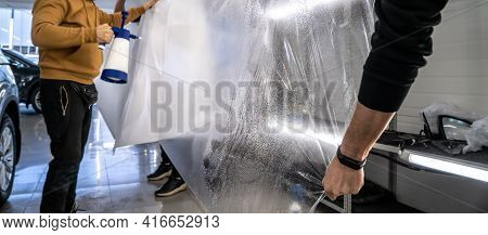 Detailer Workers Stretch And Wet By Spray Ppf Or Car Protection Film Before Installing And Pulling O