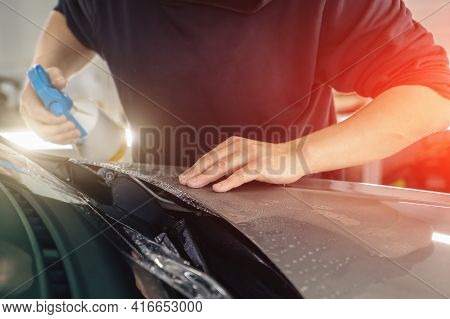 Detailer Worker Sprays By Soap Sud And Wrap Ppf Or Car Protection Film On Vehicle Hood.