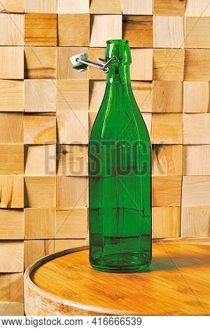 Vintage Faceted Green Bottle Of Wine On A Wooden Winery Table In The Shop. Wooden Table And Walls In