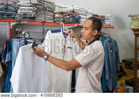 Young Asian Muslim Man Shopping For Clothes At Store