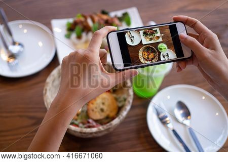 The Woman Hand Is Using A Mobile Phone To Take A Picture Of Food On The Dining Table In The Restaura