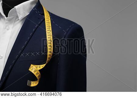 Semi-ready Jacket With Tailor's Measuring Tape On Mannequin Against Grey Background, Closeup. Space 