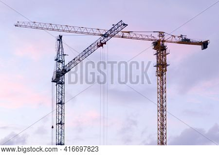 Two Construction Cranes Are Standing On A Construction Site