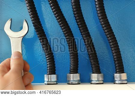 These Are Power Cables In Corrugated Insulation And A Rock Electrician With A Wrench Close Up Agains