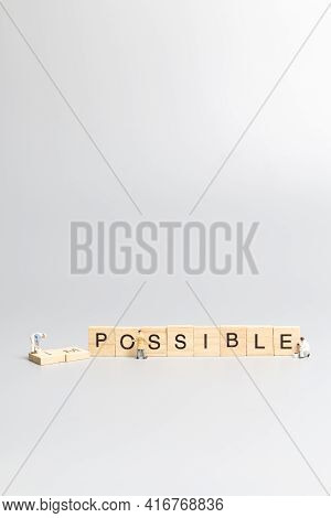 Miniature  People Worker Team On Impossible Word In Wooden Alphabet Letters