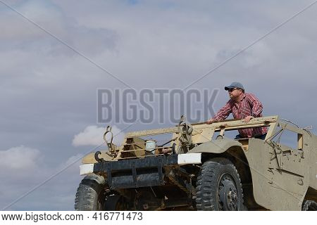 A Man In A Baseball Cap And Dark Glasses In An Old Military Vehicle