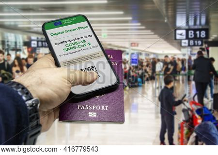 Male Hand Holding A Phone With The European Union Vaccination Certificate On The Screen And A Tradit
