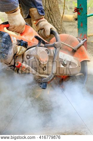 A Worker Cuts A Concrete Structure With A Portable Concrete Cutter And Diamond Blade, Creating A Clo