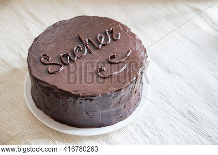 Sachertorte A Chocolate Gateau With Apricot Jam Filling And Chocolate Icing On White Plate On Light 