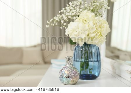 Stylish Catalytic Lamp With Beautiful Bouquet On White Table In Living Room, Space For Text. Cozy In