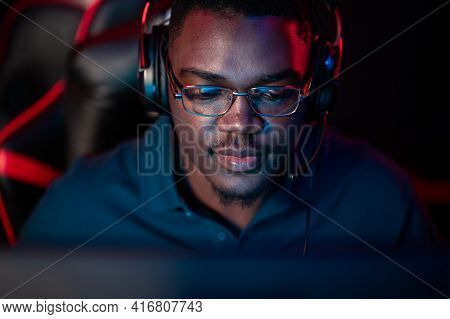 A Close-up Portrait Of A Handsome Dark-skinned Man Wearing Glasses And A Headset In Front Of A Compu