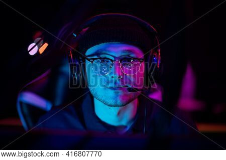 Close-up Portrait Of A Young Gamer At The Computer. A Gaming Headset With Headphones On The Head. Ne