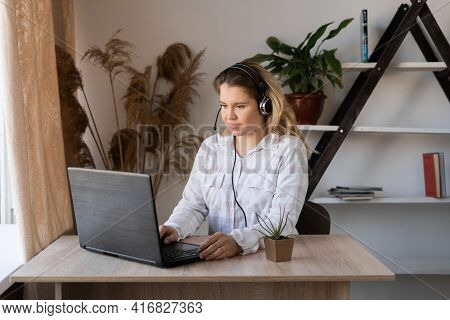 Young Student Using Laptop Sitting At Cafe Table. Blonde Female Student Using Portable Laptop Comput