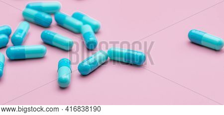 Blue Capsule Pills On Pink Background. Pharmaceutical Industry. Capsule Pill Administration. Non Dru