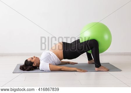 Young Flexible Pregnant Woman Doing Gymnastics On Rug On The Floor On White Background. The Concept 