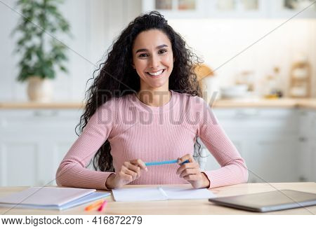 Remote Professions. Young Female Tutor Sitting At Table And Smiling At Camera