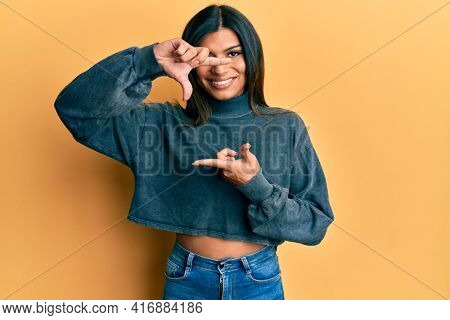 Young latin transsexual transgender woman wearing casual clothes smiling making frame with hands and fingers with happy face. creativity and photography concept. 
