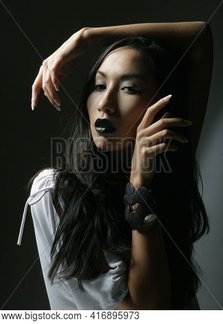 Beautiful young asian female model with black lips and long hair, wearing white bluse