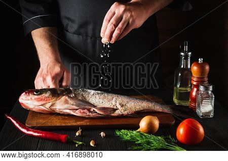 The Chef Prepares Fresh Fish Bighead Carp Sprinkling Salt With The Ingredients. Preparing To Cook Fi