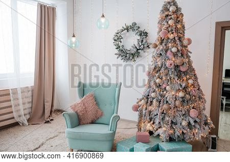 Christmas Tree With Garlands And Decorative Toys. Blue Soft Armchair