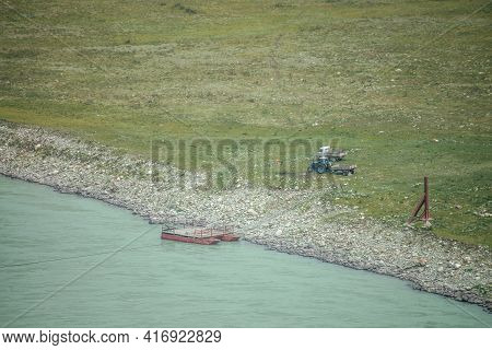 Scenic Landscape With Ferry Boat Near Stony Shore Of Wide Mountain River With Turquoise Water. Beaut