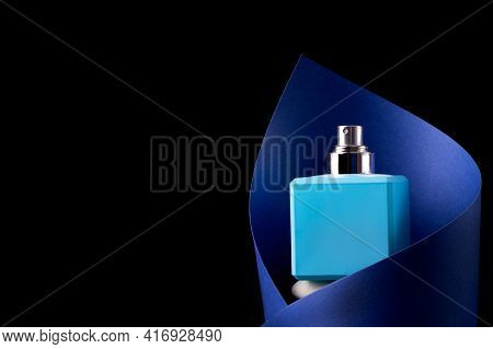 Blue Perfume Bottle Inside The Paper Cut Against The Black Background. Unlabeled Fragrance For Men A
