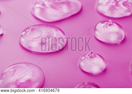 Transparent Drops Of Gel On A Pink Background With Free Space.