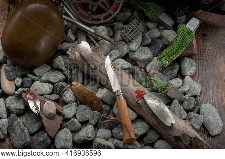 Fishing Tackle And A Knife On The Stones. Pocket Knife On Wood.