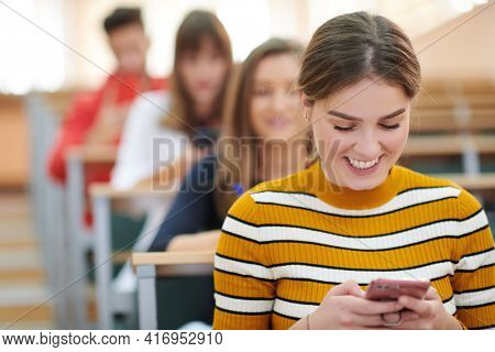 famel students using smartphone in classroom