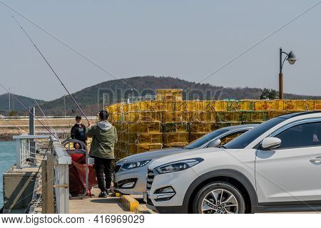 Pyeongtaek, South Korea; April 6, 2021: Two Unidentified Men Fishing Off Ocean Pier At Jeongok Marin