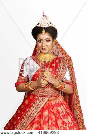 Stunning Indian Bride Dressed In Red Traditional Banarasi Sari Embroidered With Gold Jewellery And B