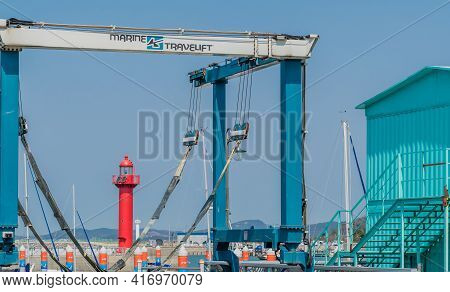 Pyeongtaek, South Korea; April 6, 2021: Red Lighthouse Seen Through Marine Boat Lift At Jeongok Port