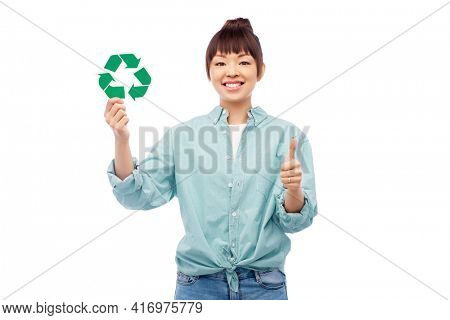eco living, environment and sustainability concept - portrait of happy smiling young asian woman in turquoise shirt holding green recycling sign over grey background