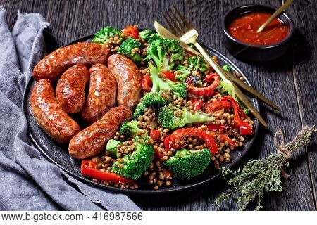 Italian Cotechino Pork Sausages Braised With Brown Lentils, Red Pepper, And Broccoli Served On A Bla