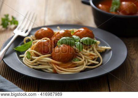 Spaghetti With Eatballs Tomato Sauce , Basil Leaves In Black Mate Plate On Wooden Background, Delici
