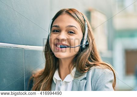Young latin call center aget girl smiling happy using headset at the city.