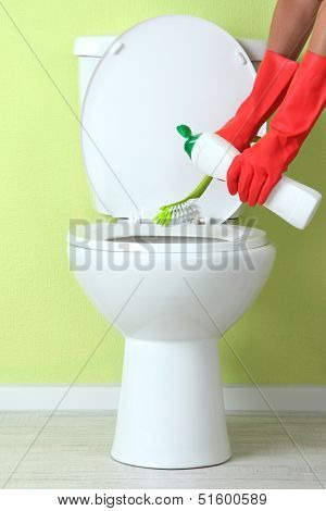 Woman hand with spray bottle cleaning a toilet bowl in a bathroom