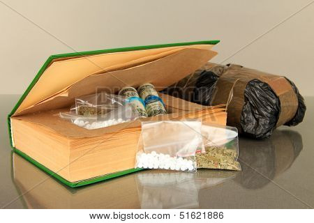 Narcotics in book-hiding place and packages on gray background