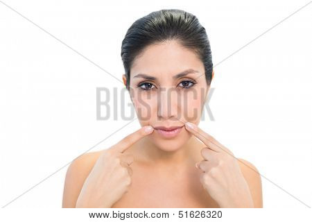 Brunette pointing to mouth and looking at camera on white background