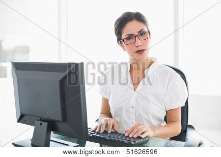 Serious businesswoman working at her desk looking at camera in her office