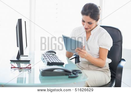 Smiling businesswoman using her digital tablet at desk in her office