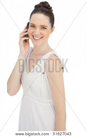 Smiling young model in white dress on white background having phone call