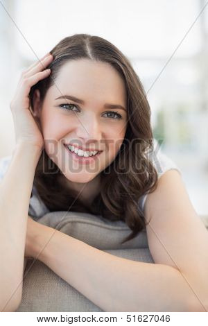 Close up on smiling cute woman lying on a cosy couch in bright living room