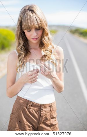 Pretty woman holding flower while walking on the road in summertime